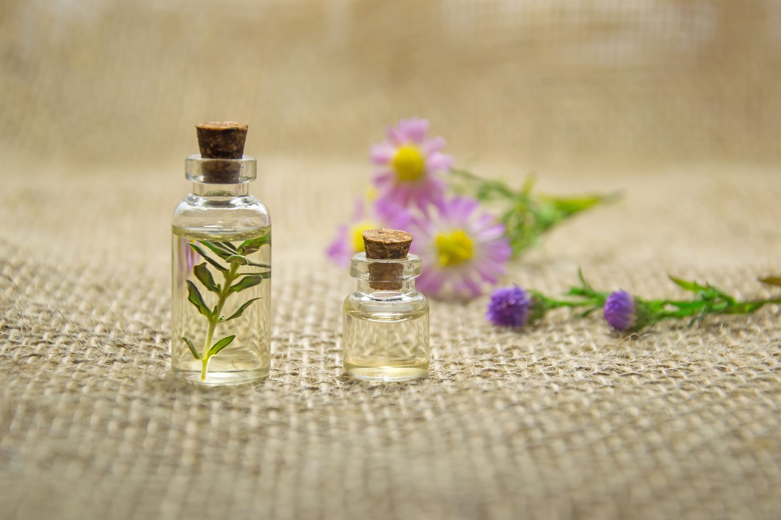 Kleine Flaschen mit ätherischen Ölen und Blüten